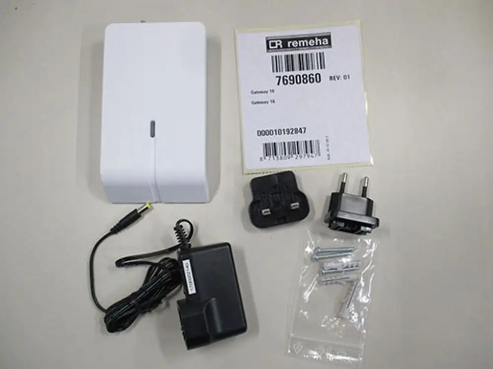 Weißes Gerät von Remeha, dazu ein Netzadapter, mehrere Steckdosenadapter und eine Tüte mit Schrauben und Dübel zur Befestigung.